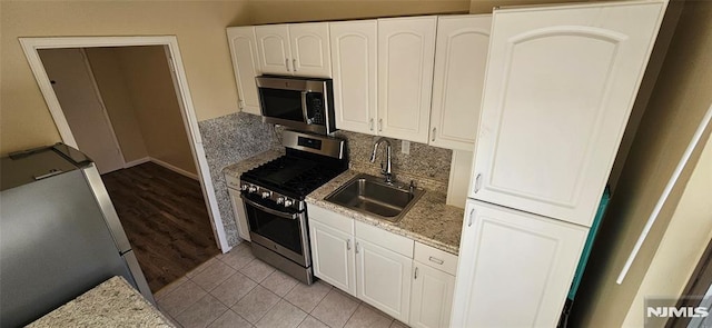 kitchen featuring sink, tasteful backsplash, appliances with stainless steel finishes, light stone countertops, and white cabinets