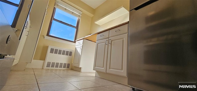 interior space with a high ceiling, radiator heating unit, and light tile patterned floors