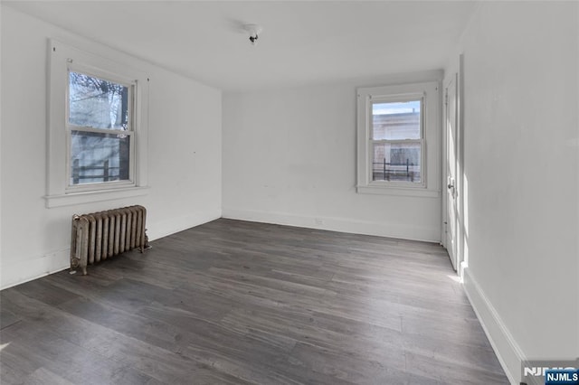 spare room with dark hardwood / wood-style flooring and radiator