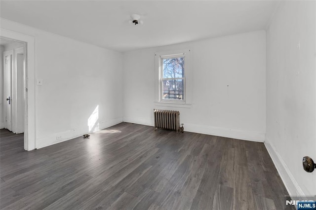 empty room with radiator and dark hardwood / wood-style flooring