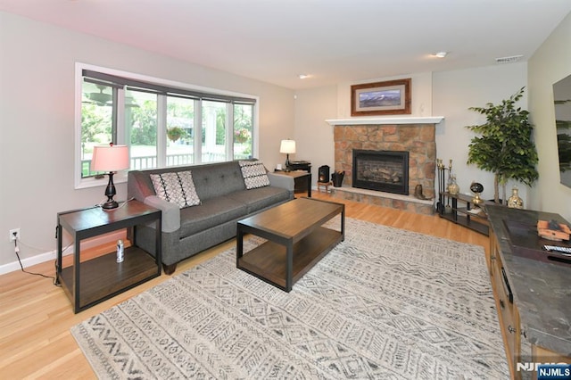 living room with a stone fireplace and light hardwood / wood-style floors