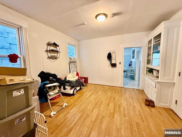 sitting room with brick wall and light hardwood / wood-style flooring