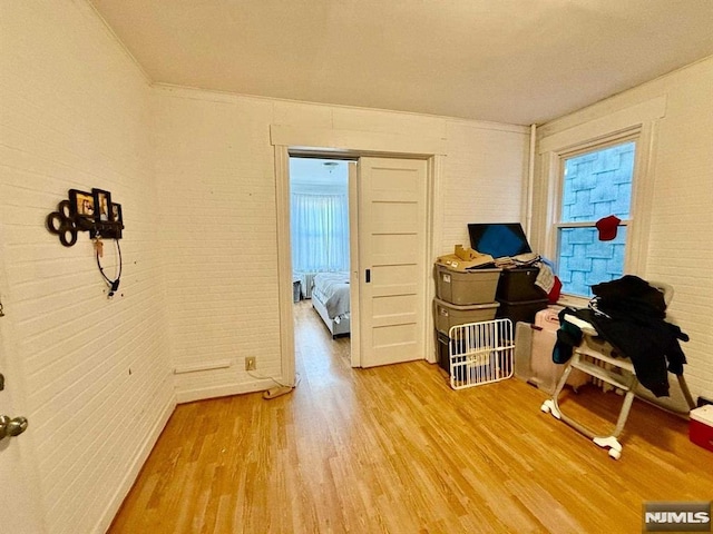 miscellaneous room with wood-type flooring and brick wall