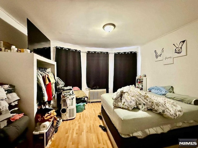 bedroom featuring radiator heating unit and wood-type flooring