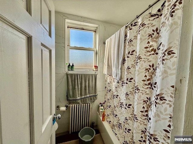 bathroom featuring radiator and shower / bath combo with shower curtain