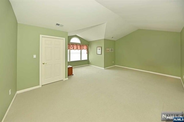 additional living space featuring light colored carpet and lofted ceiling