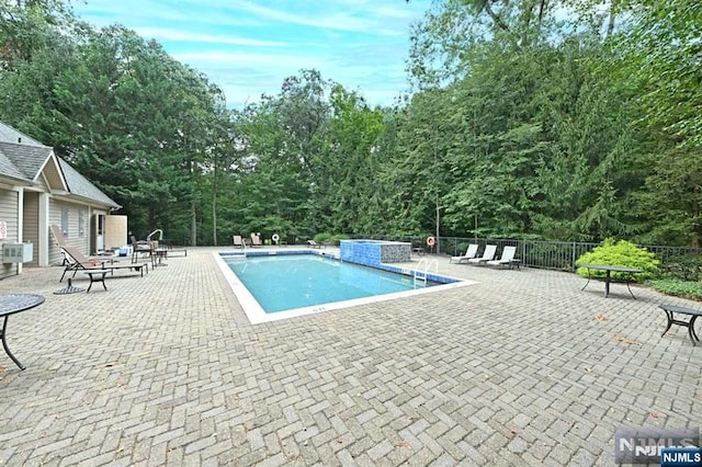 view of swimming pool featuring pool water feature and a patio area