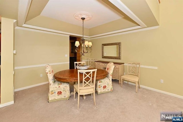 carpeted dining space with crown molding, a tray ceiling, and an inviting chandelier