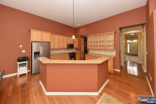 kitchen with stainless steel appliances, a kitchen island, hanging light fixtures, and light brown cabinetry