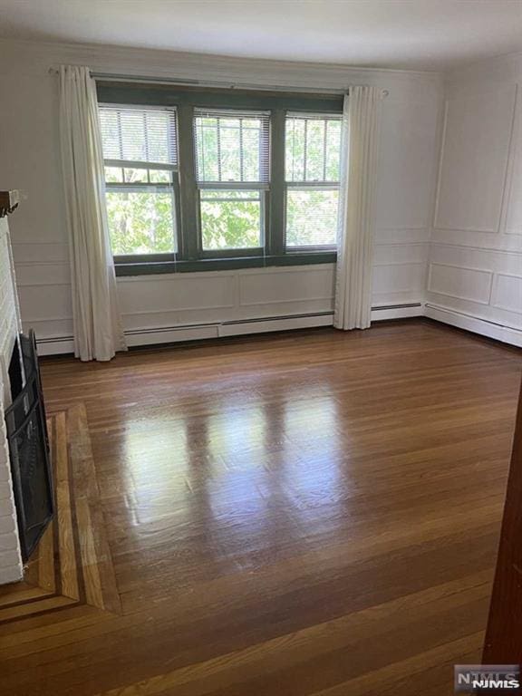 unfurnished room with wood-type flooring, plenty of natural light, and a fireplace