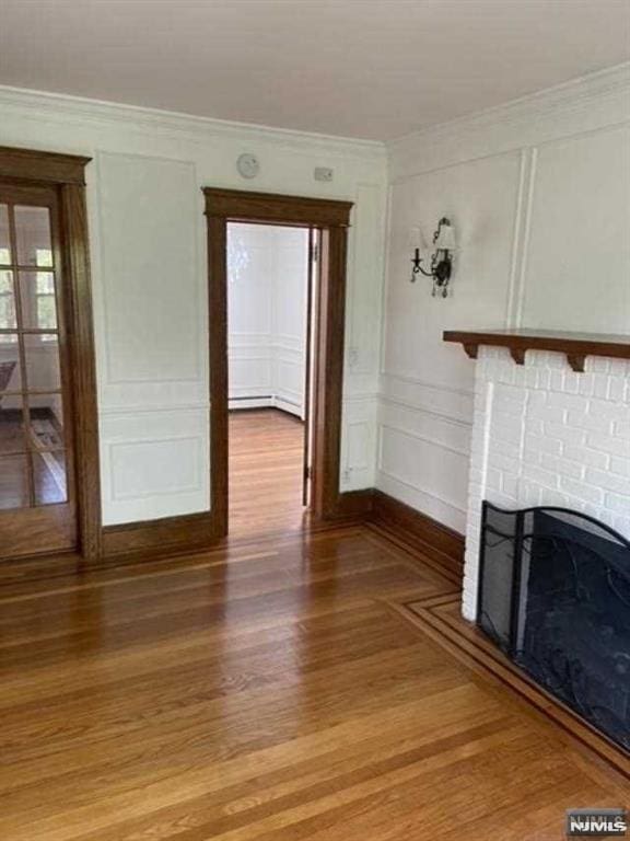 unfurnished living room with wood-type flooring, ornamental molding, and a fireplace