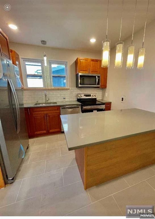 kitchen featuring sink, light tile patterned floors, hanging light fixtures, stainless steel appliances, and decorative backsplash