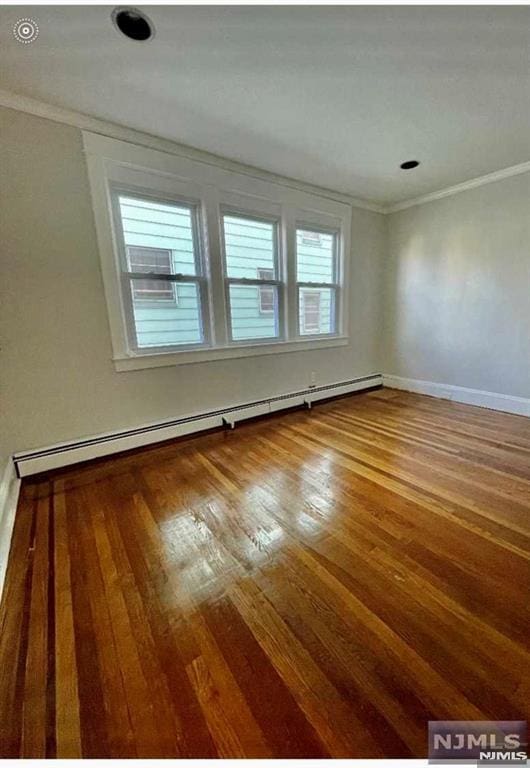 unfurnished room featuring ornamental molding, wood-type flooring, and a baseboard heating unit