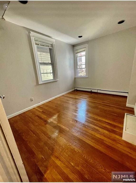 empty room with hardwood / wood-style floors and a baseboard radiator