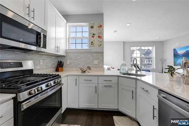 kitchen featuring dark hardwood / wood-style floors, tasteful backsplash, sink, white cabinets, and stainless steel appliances