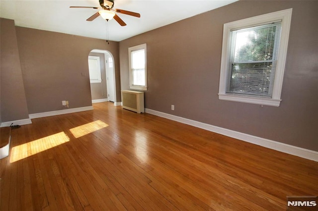 unfurnished room with hardwood / wood-style floors, radiator heating unit, and ceiling fan