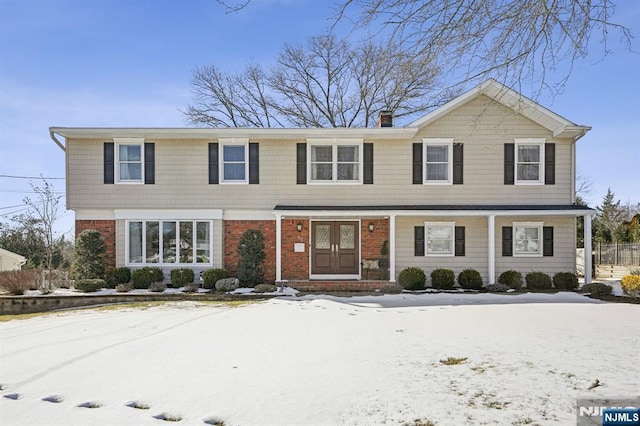 view of front of home featuring a chimney and brick siding