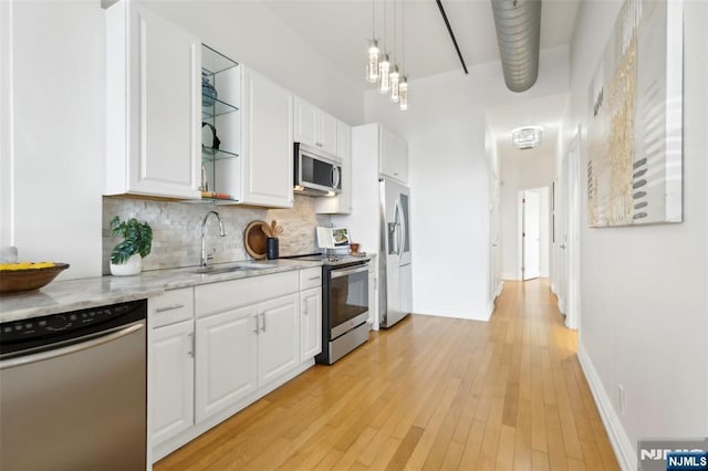 kitchen with sink, white cabinetry, light stone counters, appliances with stainless steel finishes, and pendant lighting