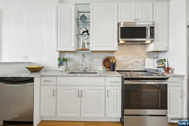 kitchen with white cabinetry, sink, stainless steel appliances, and light stone countertops