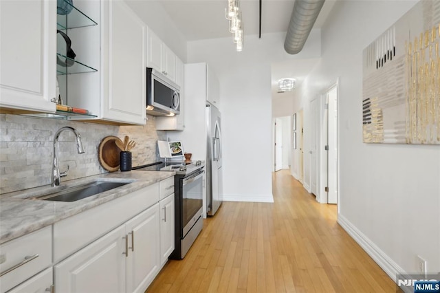 kitchen with tasteful backsplash, sink, white cabinets, stainless steel appliances, and light stone countertops