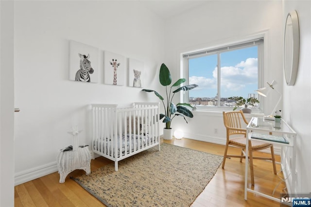 bedroom featuring hardwood / wood-style floors and a crib