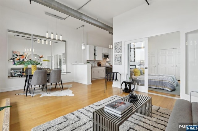 living room featuring sink, a high ceiling, and light wood-type flooring