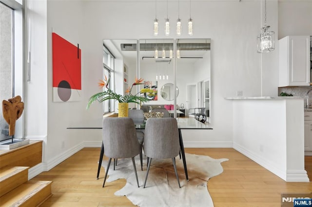 dining room with a high ceiling, a chandelier, and light hardwood / wood-style floors