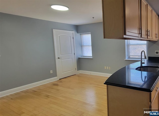 kitchen featuring sink, dark stone countertops, and light hardwood / wood-style flooring