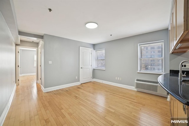 interior space with dark stone counters, a wall mounted AC, and light wood-type flooring