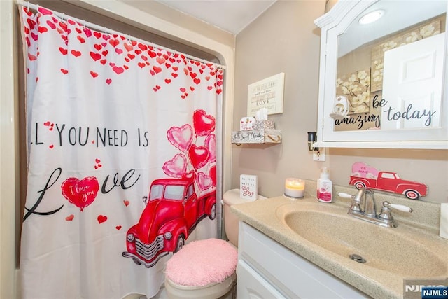 bathroom with walk in shower, vanity, and toilet