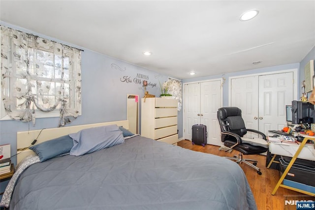 bedroom featuring light wood-type flooring and two closets