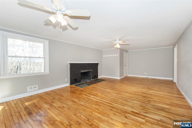 unfurnished living room with a brick fireplace, ornamental molding, light hardwood / wood-style floors, and ceiling fan