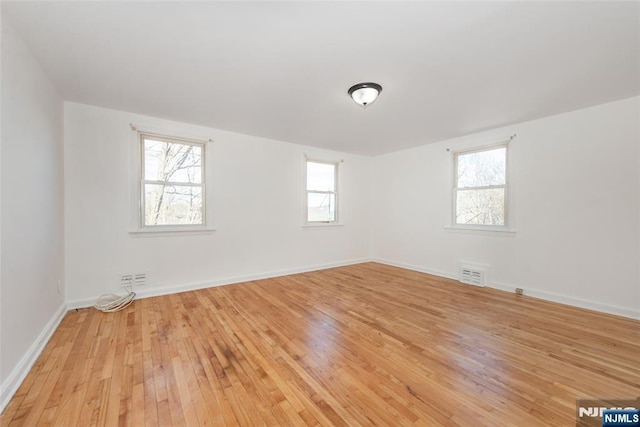 empty room with plenty of natural light and light hardwood / wood-style flooring