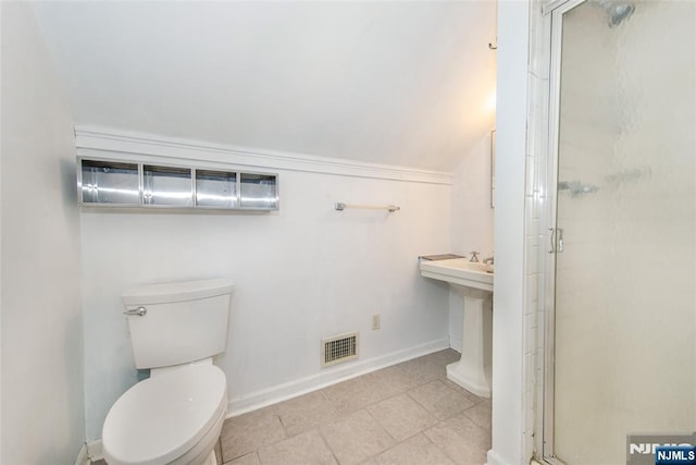 bathroom featuring lofted ceiling, toilet, a shower with shower door, and sink