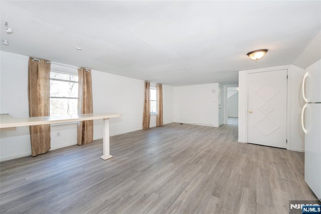 basement featuring light hardwood / wood-style floors and white fridge