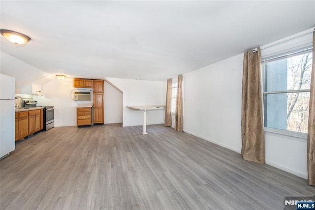 unfurnished living room featuring vaulted ceiling and light wood-type flooring