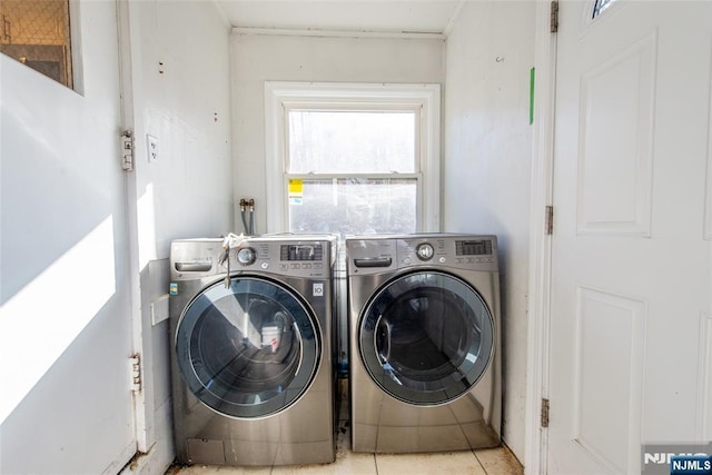 clothes washing area with light tile patterned floors and washer and dryer