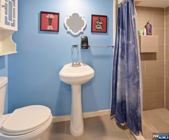 bathroom featuring toilet, tile patterned floors, and a shower with shower curtain