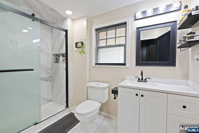 bathroom featuring tile patterned floors, vanity, toilet, and a shower with shower door