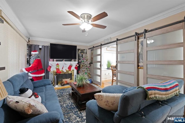 living room with wood-type flooring, ornamental molding, a barn door, and ceiling fan