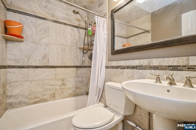 full bathroom with shower / bathtub combination with curtain, sink, tile walls, and toilet