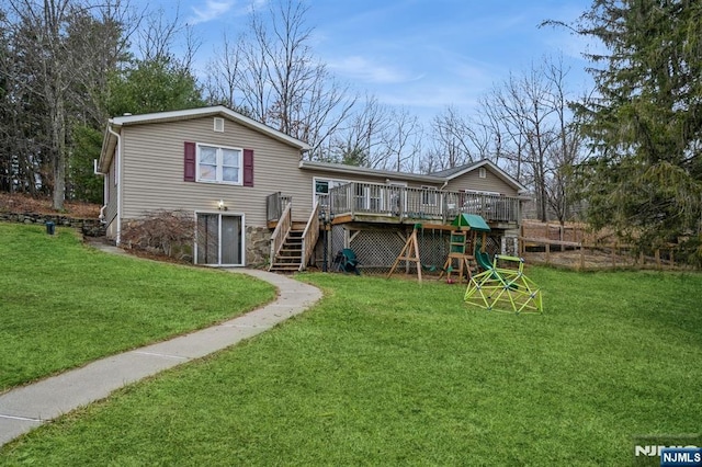 rear view of property with a wooden deck, a lawn, and a playground