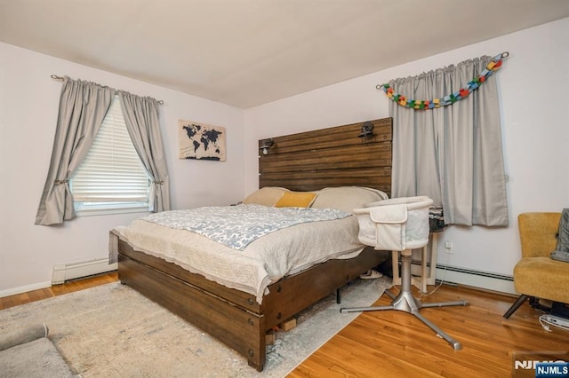 bedroom with hardwood / wood-style flooring and a baseboard heating unit