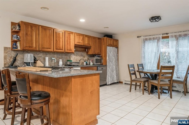 kitchen with stone countertops, dishwasher, a kitchen breakfast bar, decorative backsplash, and kitchen peninsula