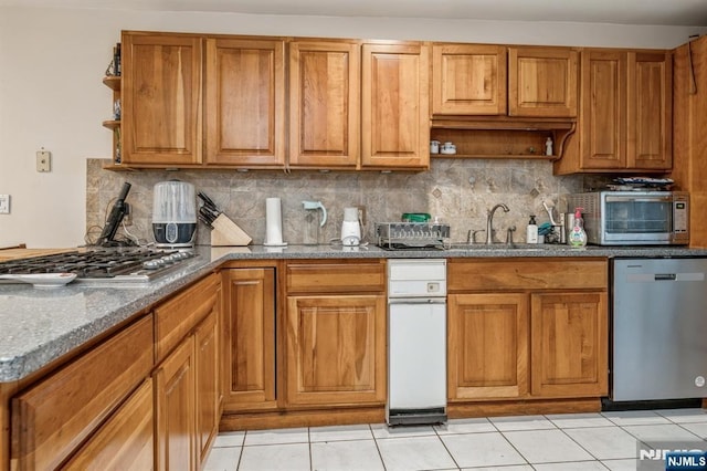 kitchen featuring light tile patterned flooring, appliances with stainless steel finishes, sink, and light stone counters