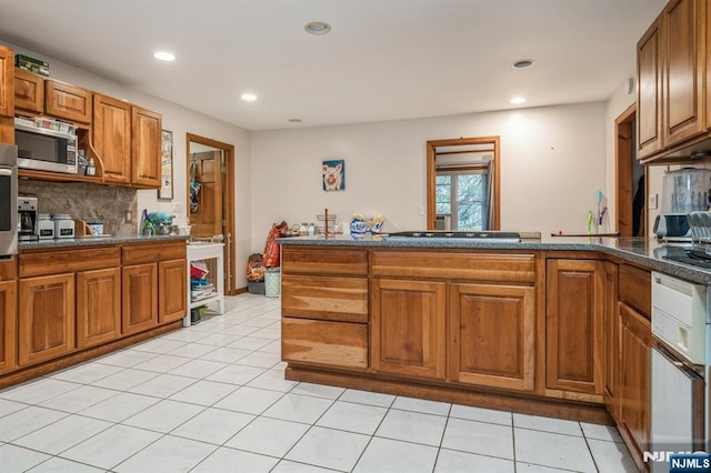 kitchen with tasteful backsplash, appliances with stainless steel finishes, kitchen peninsula, and light tile patterned floors