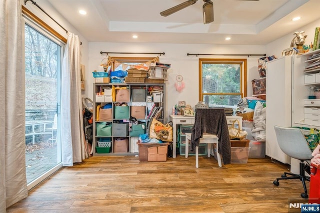 office area with ceiling fan, a raised ceiling, and light wood-type flooring