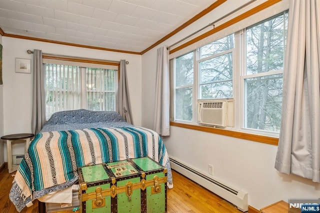 bedroom featuring crown molding, a baseboard radiator, multiple windows, and hardwood / wood-style flooring