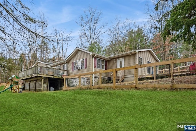 back of property featuring a playground, a yard, and a deck