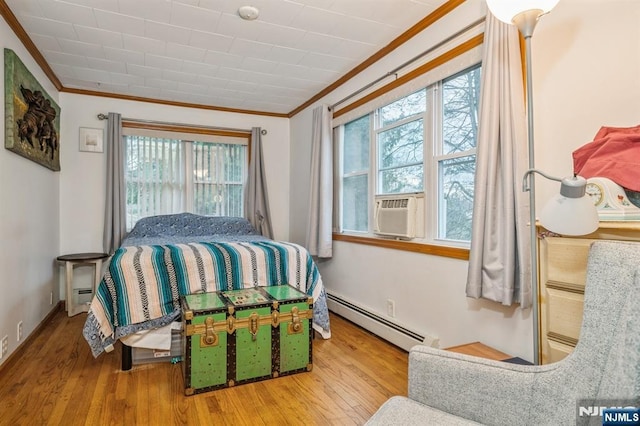 bedroom featuring multiple windows, ornamental molding, a baseboard heating unit, and hardwood / wood-style floors